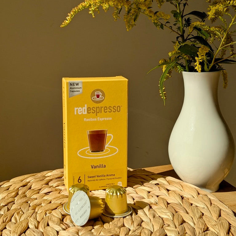 Vanilla red espresso Kapseln in gelb für Nespresso Maschine - goldene Rooibos Espresso Kapseln auf Tisch mit Blumenvase
