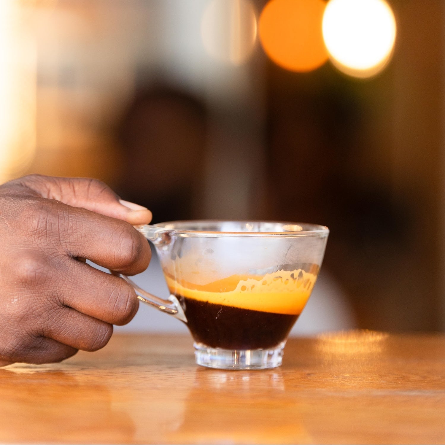 Tasse mit Rooibos Espreso Shot. Hand hält Tasse und schwingt den Rooibos Espresso mit Crema